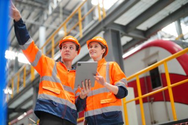 Demiryolu mühendisliği tesisinde lokomotifi inceleyen mühendisler