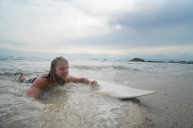 Sörf tahtasında yüzen yakışıklı genç adam.