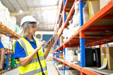 Büyük bir depoda çalışan kadın işçi. Paketler kontrol ediliyor