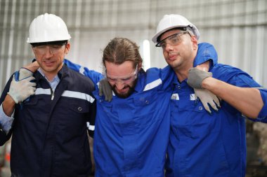 Fabrikada endüstriyel yaralanan işçiler ve bacağından yaralanan meslektaşları ona yardım ediyor..