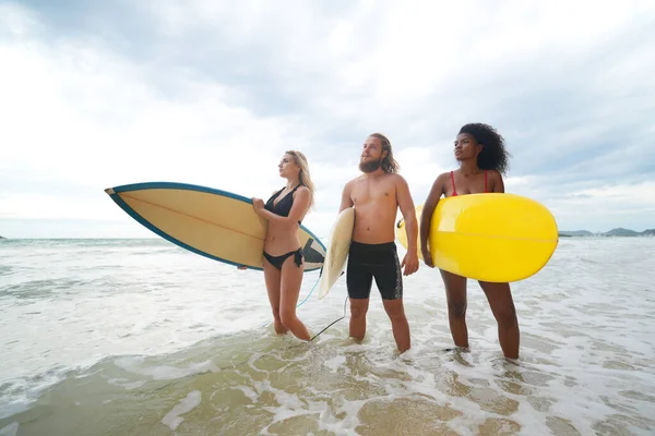 年轻的女性和男性冲浪者在海滩享受时光 — 图库照片