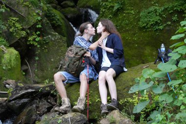 Yürüyüşçüler dağda yürüyüş sopalarıyla bir patika boyunca yürüyorlar. Macera, seyahat, turizm, yürüyüş ve insan konsepti. Sırt çantalı bir grup gülen arkadaş..