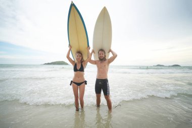 Pattaya, Tayland 'da sörf tahtasıyla sahilde sörf yapan mutlu çift..