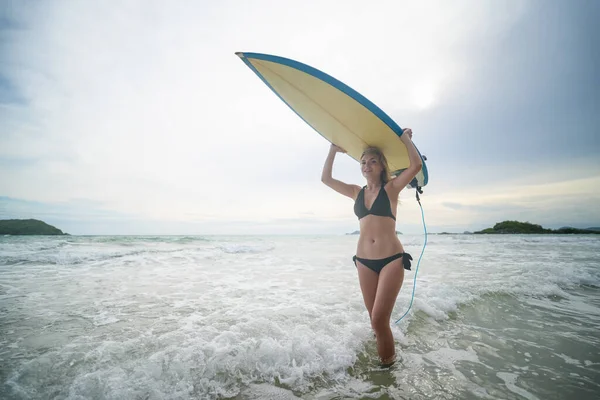 Plajda sörf tahtası olan kadın.