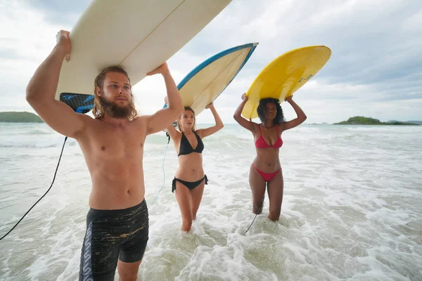 年轻的混血种族妇女和白人妇女和男子与他们的朋友一起在海滩上享受他们的时光 手握冲浪板 — 图库照片