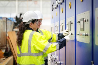 Fabrikada sanayi işçisi. Turuncu şapkalı genç teknisyen. Kafkasyalı akıllı fabrika işçisi başlık takıyor ve elektrik santralinde çalışıyor..