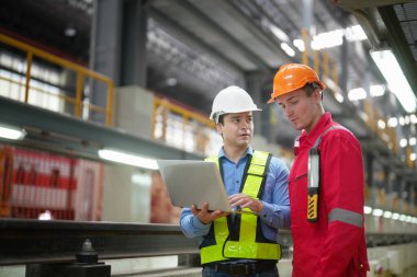 Öğretmen demiryolu mühendislik tesisinde çıraklarla konuşuyor.