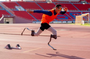 Stadyumdaki koşu pistinde protez bıçaklı Asyalı sporcular.