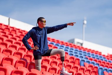 Stadyumdaki koşu pistinde protez bıçaklı Asyalı atletler. Futbol stadyumundaki koltuklar