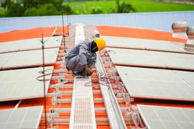 Uzman teknisyen profesyonel mühendis güneş ışığı altında fabrikanın çatısına güneş paneli kurarken üst görüntüyü kontrol ediyor. Elektrik yenilenebilir eko enerji hizmeti veren mühendisler