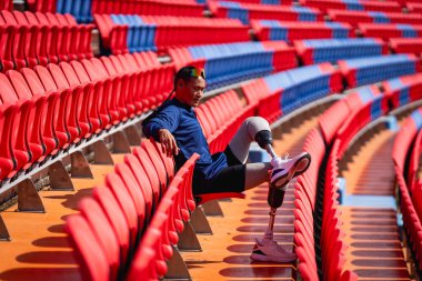 Stadyumdaki koşu pistinde protez bıçaklı Asyalı atletler. Futbol stadyumundaki koltuklar