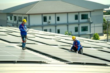 Profesyonel mühendisler güneş ışığı altında güneş çatılarını kontrol ediyorlar. Elektrik yenilenebilir enerji hizmeti veren mühendisler