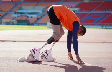 Stadyumdaki koşu pistinde protez bıçaklı Asyalı sporcular.
