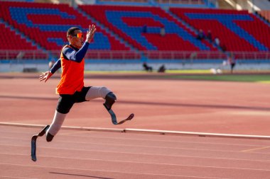 Stadyumdaki koşu pistinde protez bıçaklı Asyalı sporcular.