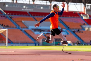 Stadyumdaki koşu pistinde protez bıçaklı Asyalı sporcular.