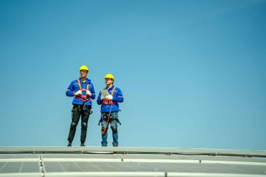 Profesyonel mühendisler güneş ışığı altında güneş çatılarını kontrol ediyorlar. Elektrik yenilenebilir enerji hizmeti veren mühendisler
