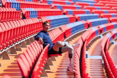 Stadyumdaki koşu pistinde protez bıçaklı Asyalı atletler. Futbol stadyumundaki koltuklar