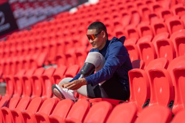 Stadyumdaki koşu pistinde protez bıçaklı Asyalı atletler. Futbol stadyumundaki koltuklar