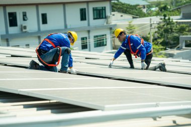 Uzman teknisyen profesyonel mühendis güneş ışığı altında fabrikanın çatısına güneş paneli kurarken üst görüntüyü kontrol ediyor. Elektrik yenilenebilir eko enerji hizmeti veren mühendisler