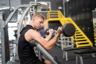 Spor salonundaki yakışıklı, formda adam halter kaldırıyor.