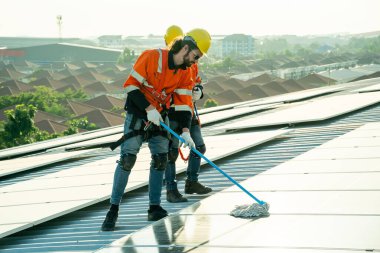 Uzman teknisyen profesyonel mühendis güneş ışığı altında fabrikanın çatısına güneş paneli kurarken üst görüntüyü kontrol ediyor. Elektrik yenilenebilir eko enerji hizmeti veren mühendisler