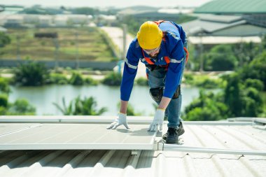 Profesyonel mühendis güneş ışığı altında fabrikanın çatısındaki güneş panelini kontrol ediyor. Elektrik yenilenebilir eko enerji hizmeti veren bir mühendis.