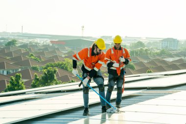 Uzman teknisyen profesyonel mühendis güneş ışığı altında fabrikanın çatısına güneş paneli kurarken üst görüntüyü kontrol ediyor. Elektrik yenilenebilir eko enerji hizmeti veren mühendisler