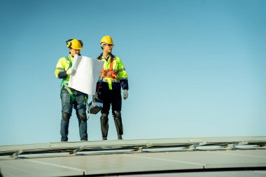 Profesyonel mühendisler güneş ışığı altında güneş çatılarını kontrol ediyorlar. Elektrik yenilenebilir enerji hizmeti veren mühendisler