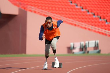 Stadyumdaki koşu pistinde protez bıçaklı Asyalı sporcular.