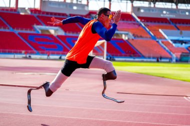 Stadyumdaki koşu pistinde protez bıçaklı Asyalı sporcular.