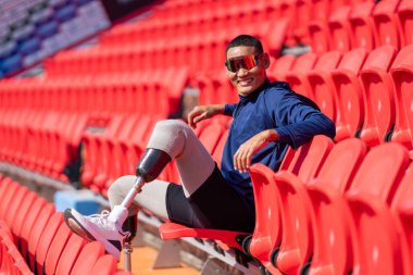 Stadyumdaki koşu pistinde protez bıçaklı Asyalı atletler. Futbol stadyumundaki koltuklar