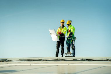 Profesyonel mühendisler güneş ışığı altında güneş çatılarını kontrol ediyorlar. Elektrik yenilenebilir enerji hizmeti veren mühendisler