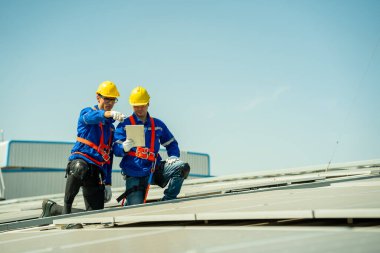 Profesyonel mühendisler güneş ışığı altında güneş çatılarını kontrol ediyorlar. Elektrik yenilenebilir enerji hizmeti veren mühendisler