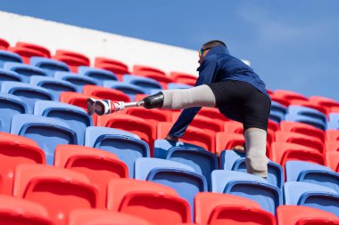 Stadyumdaki koşu pistinde protez bıçaklı Asyalı atletler. Futbol stadyumundaki koltuklar