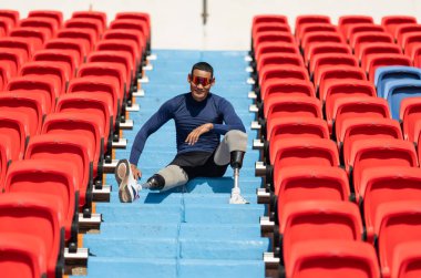 Stadyumdaki koşu pistinde protez bıçaklı Asyalı atletler. Futbol stadyumundaki koltuklar