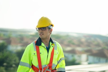 Profesyonel mühendis güneş ışığı altında fabrikanın çatısındaki güneş panelini kontrol ediyor. Elektrik yenilenebilir eko enerji hizmeti veren bir mühendis.