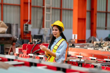 Fabrikada koruyucu giysili bir kadın. Makinede kendine güvenen kadın mühendis.