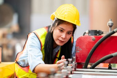 Fabrikada koruyucu giysili bir kadın. Makinede kendine güvenen kadın mühendis.