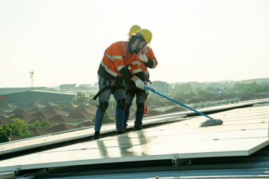 Uzman teknisyen profesyonel mühendis güneş ışığı altında fabrikanın çatısına güneş paneli kurarken üst görüntüyü kontrol ediyor. Elektrik yenilenebilir eko enerji hizmeti veren mühendisler