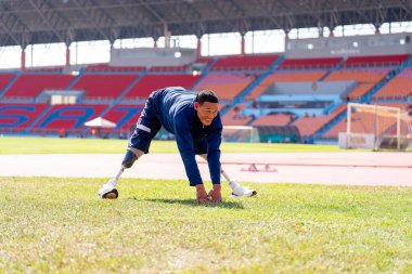 Stadyumdaki koşu pistinde protez bıçaklı Asyalı sporcular.