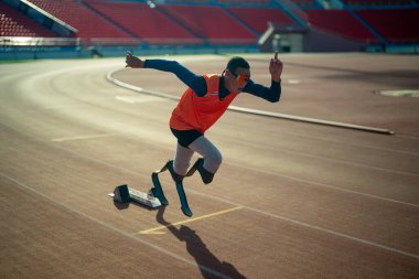 Stadyumdaki koşu pistinde protez bıçaklı Asyalı sporcular.