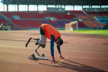 Stadyumdaki koşu pistinde protez bıçaklı Asyalı sporcular.