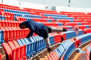 Stadyumdaki koşu pistinde protez bıçaklı Asyalı atletler. Futbol stadyumundaki koltuklar