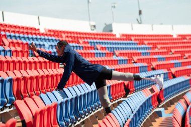 Stadyumdaki koşu pistinde protez bıçaklı Asyalı atletler. Futbol stadyumundaki koltuklar
