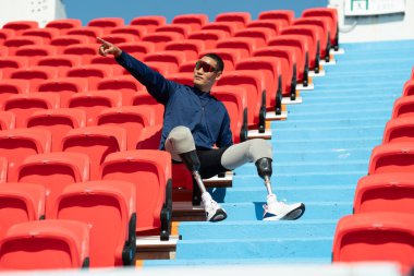 Stadyumdaki koşu pistinde protez bıçaklı Asyalı atletler. Futbol stadyumundaki koltuklar