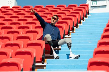 Stadyumdaki koşu pistinde protez bıçaklı Asyalı atletler. Futbol stadyumundaki koltuklar