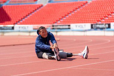 Stadyumdaki koşu pistinde protez bıçaklı Asyalı sporcular.