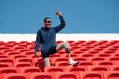 Stadyumdaki koşu pistinde protez bıçaklı Asyalı atletler. Futbol stadyumundaki koltuklar