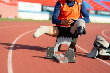 Stadyumdaki koşu pistinde protez bıçaklı Asyalı sporcular.