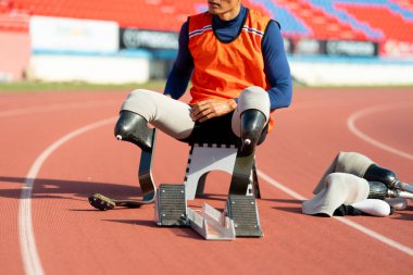 Stadyumdaki koşu pistinde protez bıçaklı Asyalı sporcular.